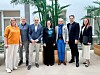 Seitse inimest seisavad siseruumis rühmapildil, taustal suured rohelised taimed ja hele fuajee.